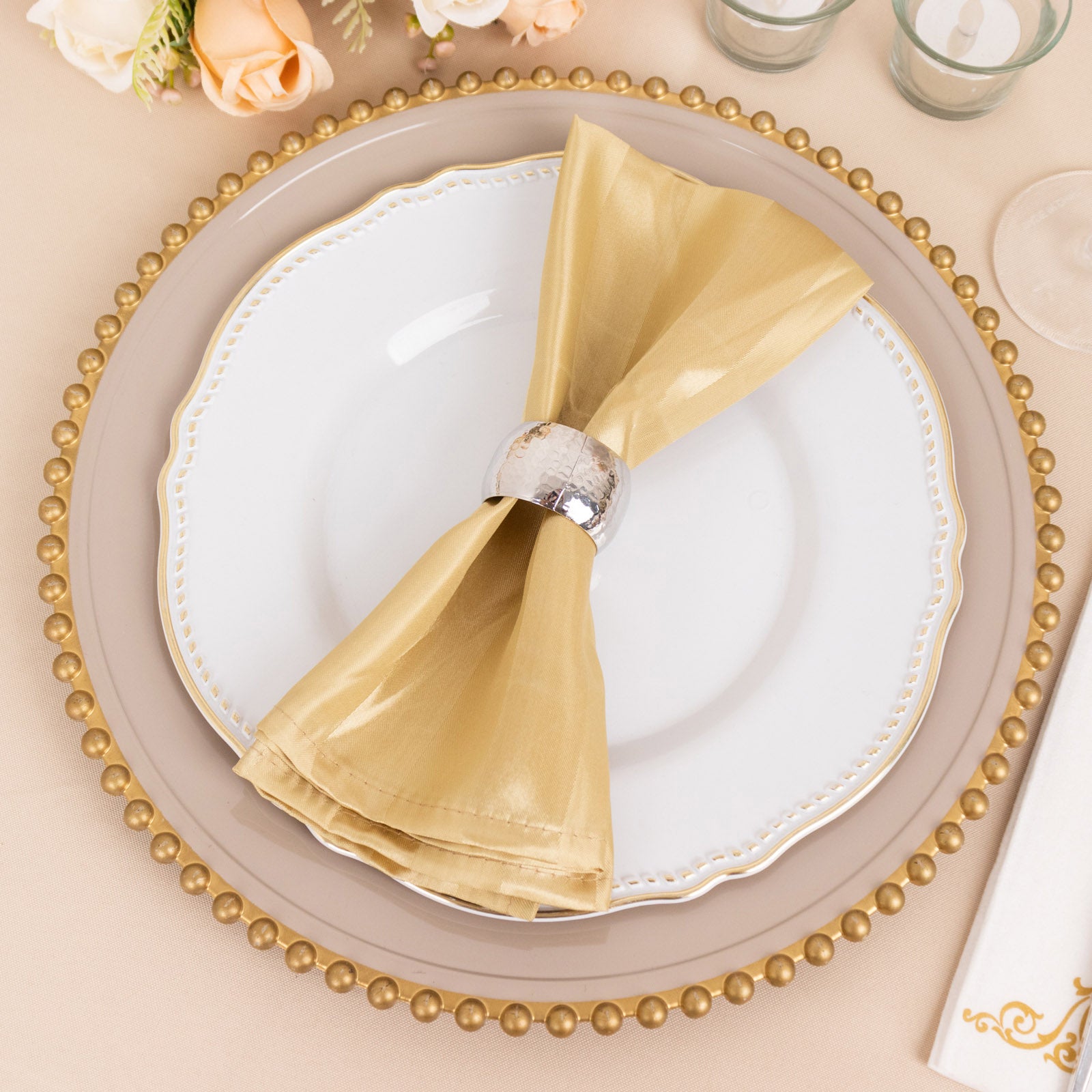 Champagne satin linen napkin on an elegant dinner plate setting.