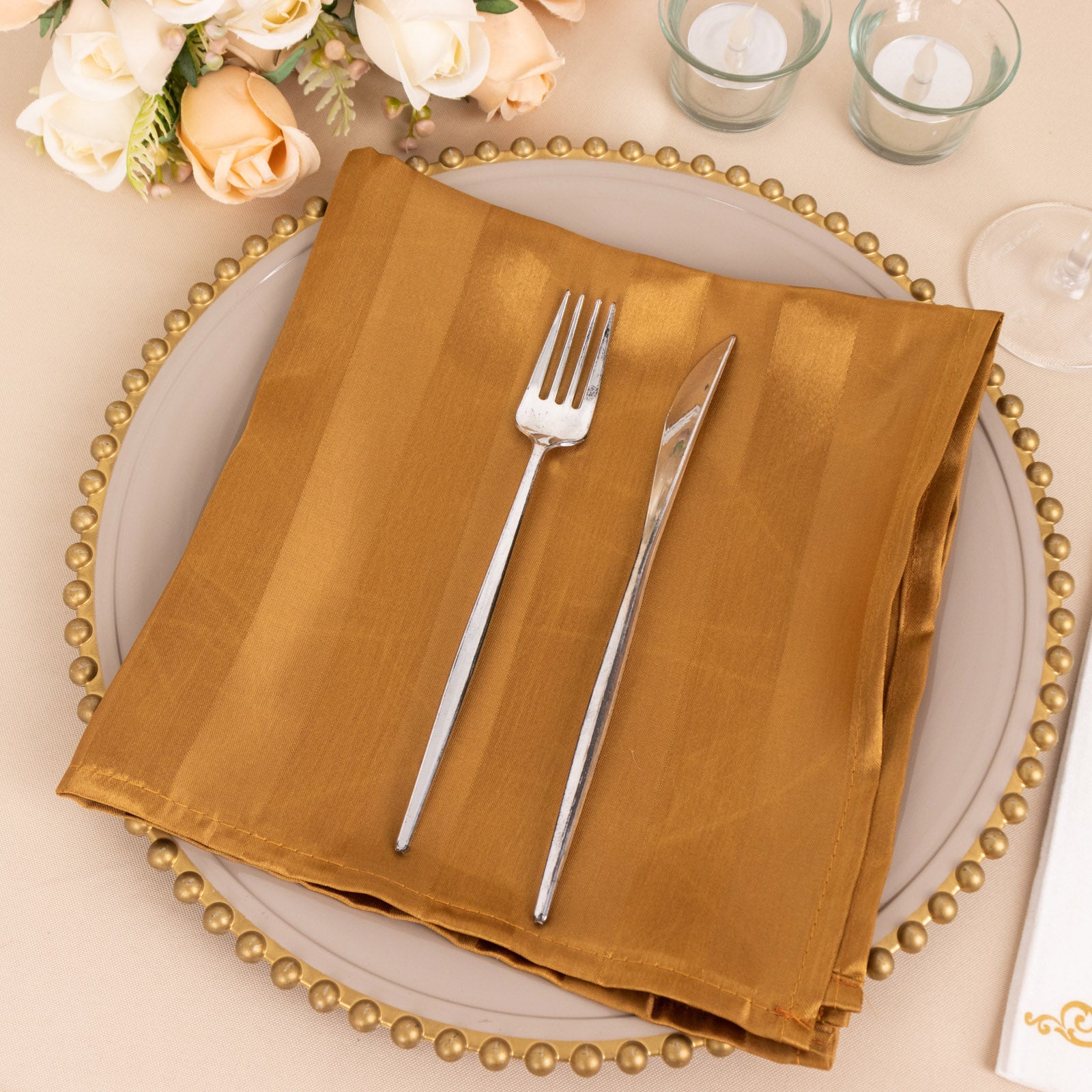 Gold striped satin napkin on a plate, elegant wedding table setting.