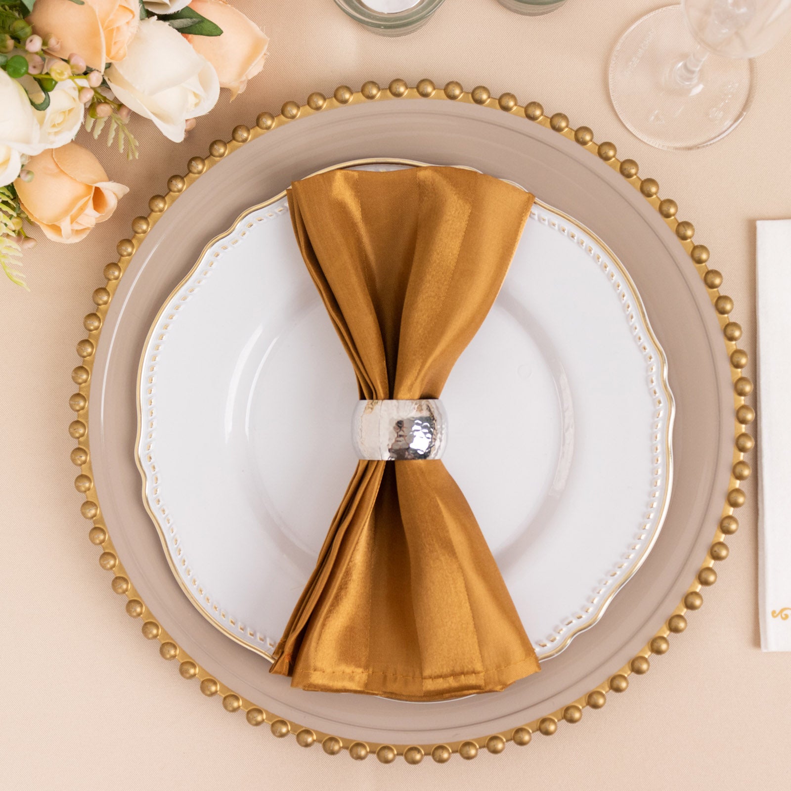 Gold satin linen napkin with a wrinkle-free finish on a decorative plate.