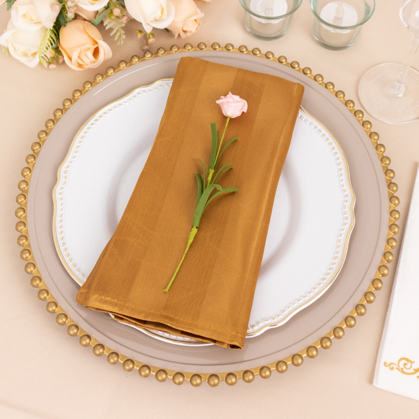 Gold striped satin napkin on a decorative plate with a flower.