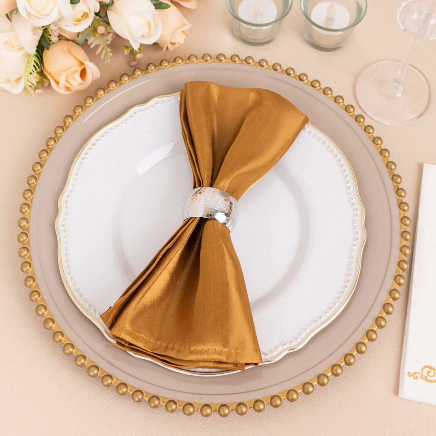 Gold satin linen napkin elegantly placed on a decorative plate.