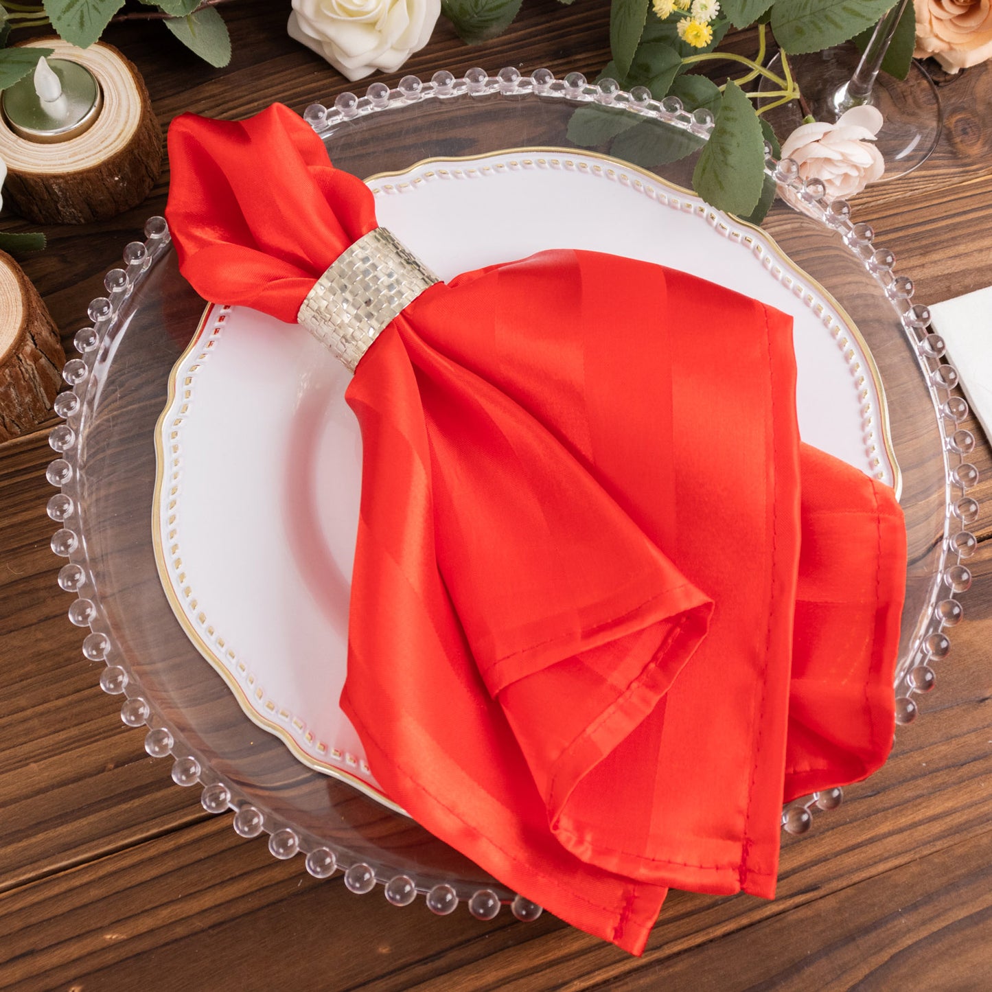 Red satin linen napkin with stripes on a decorative plate.
