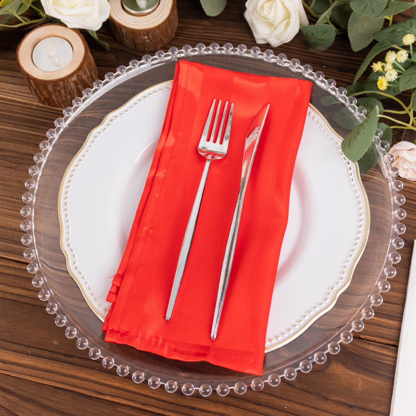 Red striped satin linen napkin on a plate with cutlery, set for a wedding.