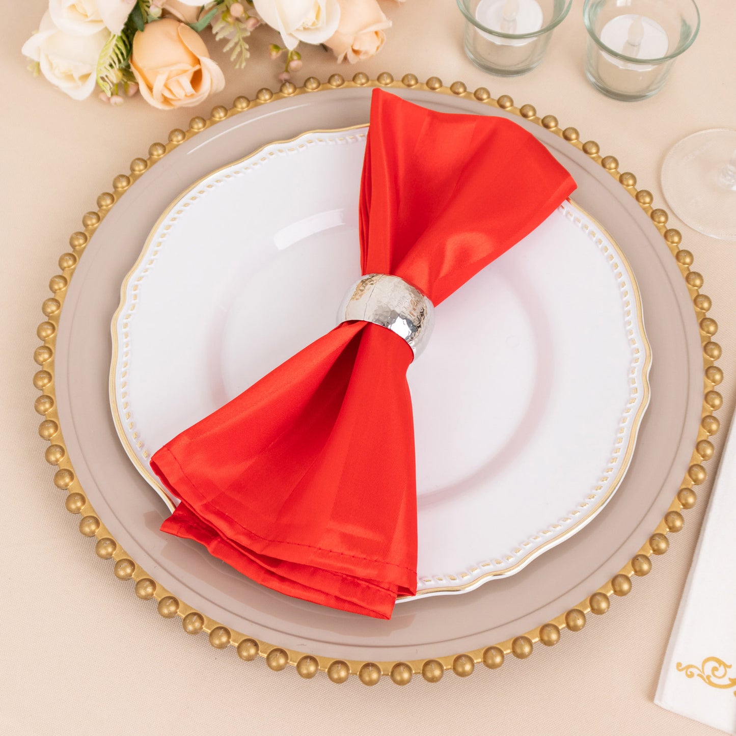 Red satin napkin elegantly arranged on a plate with gold accents.