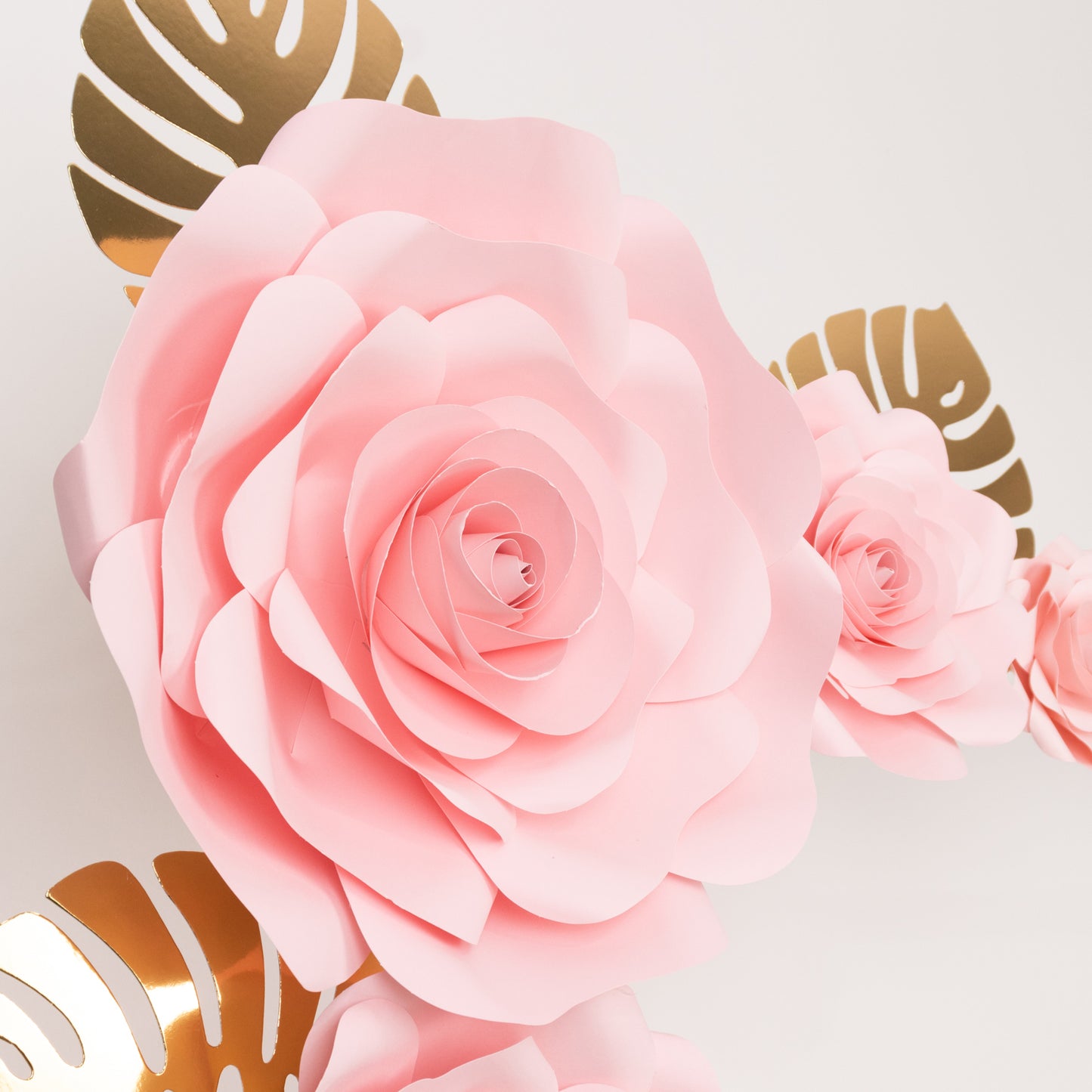 Pink 3D rose paper flowers with gold palm leaves for wall decor.