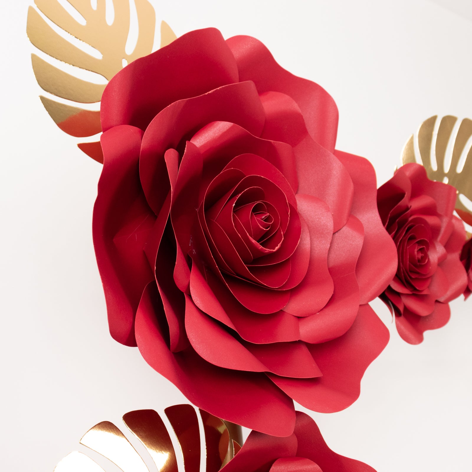 Red 3D rose paper flowers with gold tropical palm leaves for wall decor.