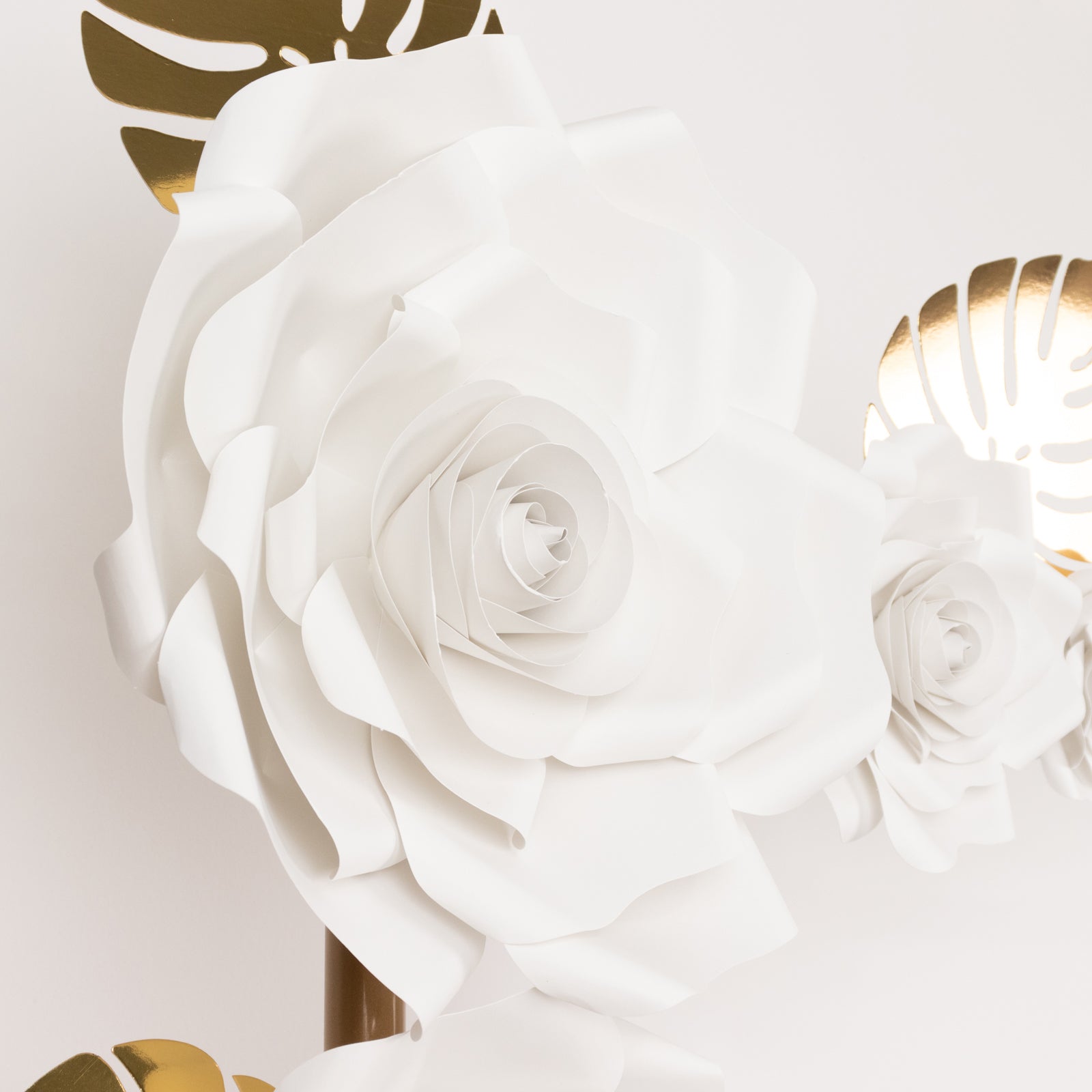 White 3D rose paper flowers with gold tropical palm leaves for decor.