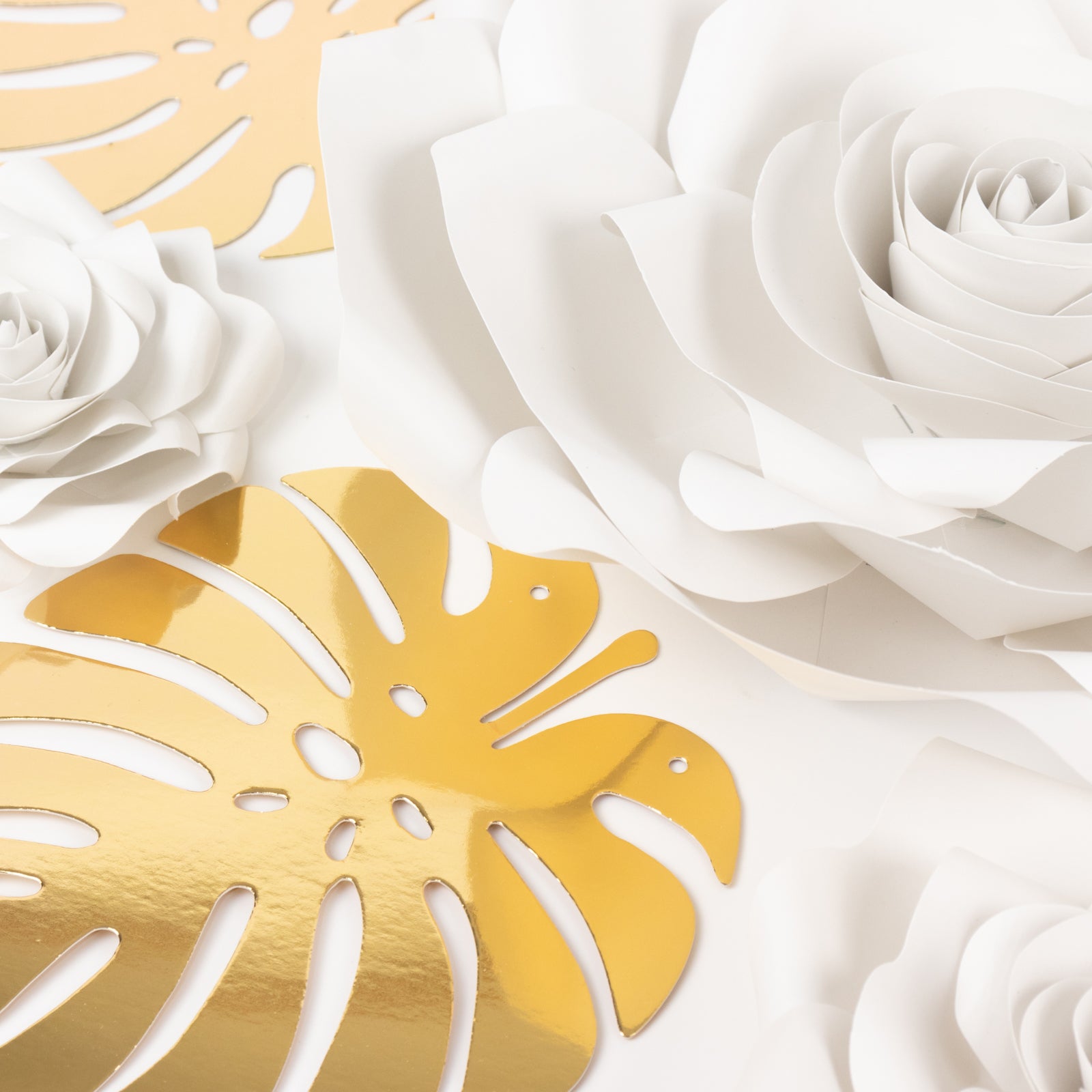 White 3D rose paper flowers with gold tropical palm leaves decor.