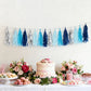Blue and silver foil tassel garland decoration over a festive table setting.