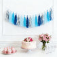 Blue and silver foil tassel garland banner decoration with cake and flowers.