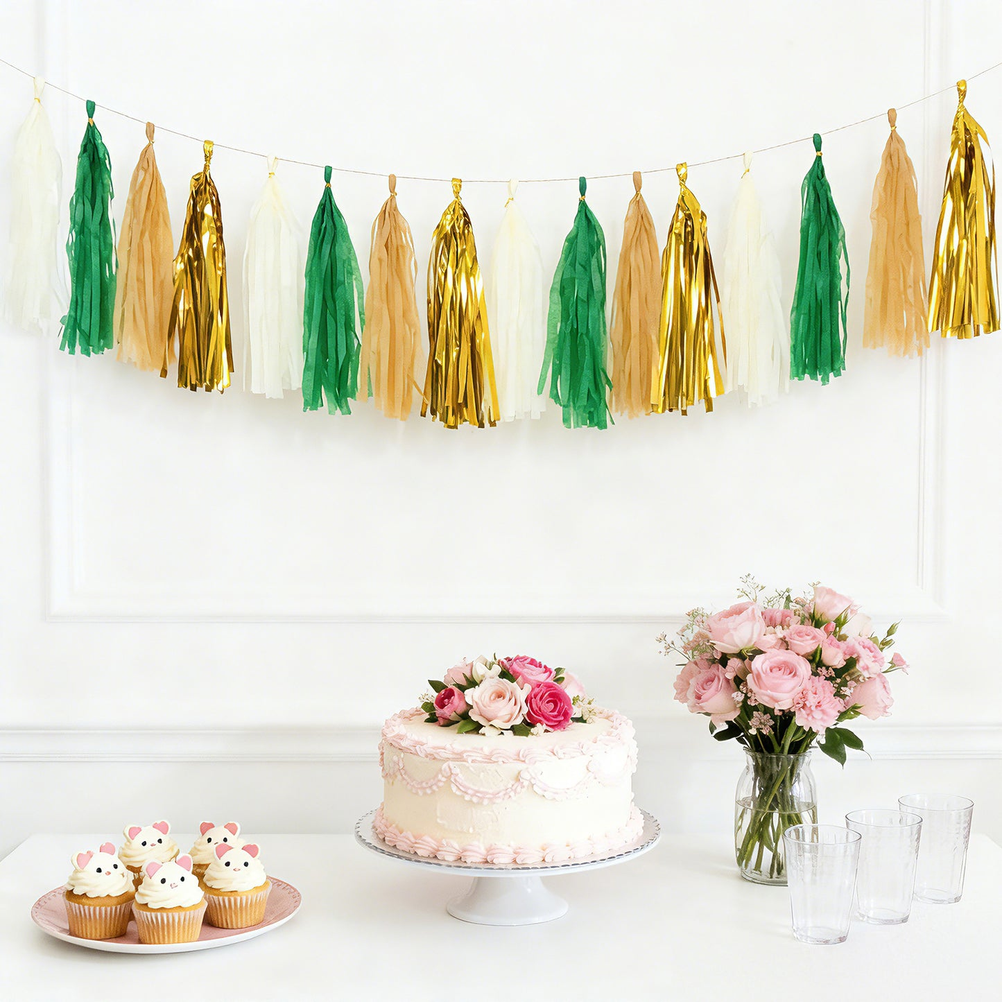 Gold and green foil tassel garland banner decoration above a cake and cupcakes.