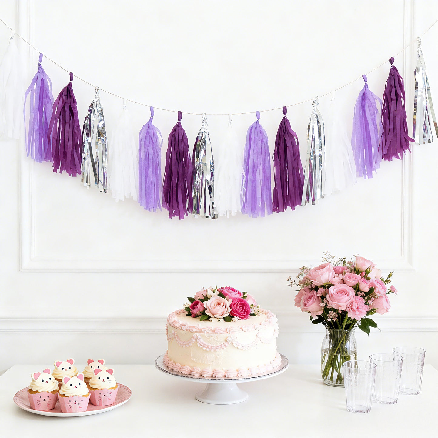 Purple and silver tassel garland banner decoration with cupcakes and cake.