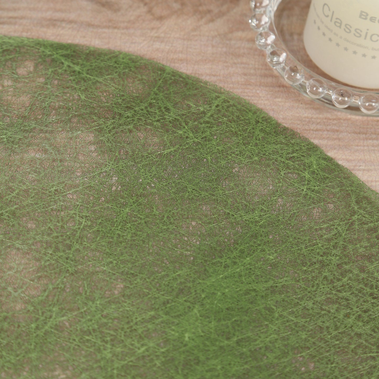 Olive green disposable round placemat on a wooden table.