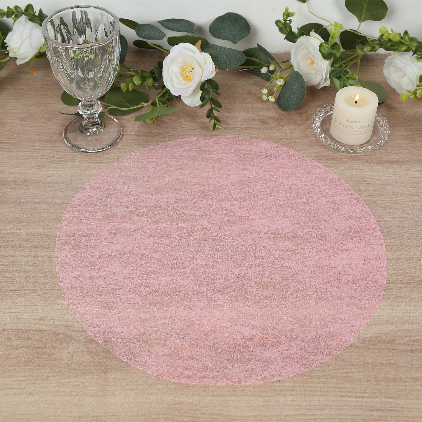 Pink disposable placemat on a dining table with floral decor.