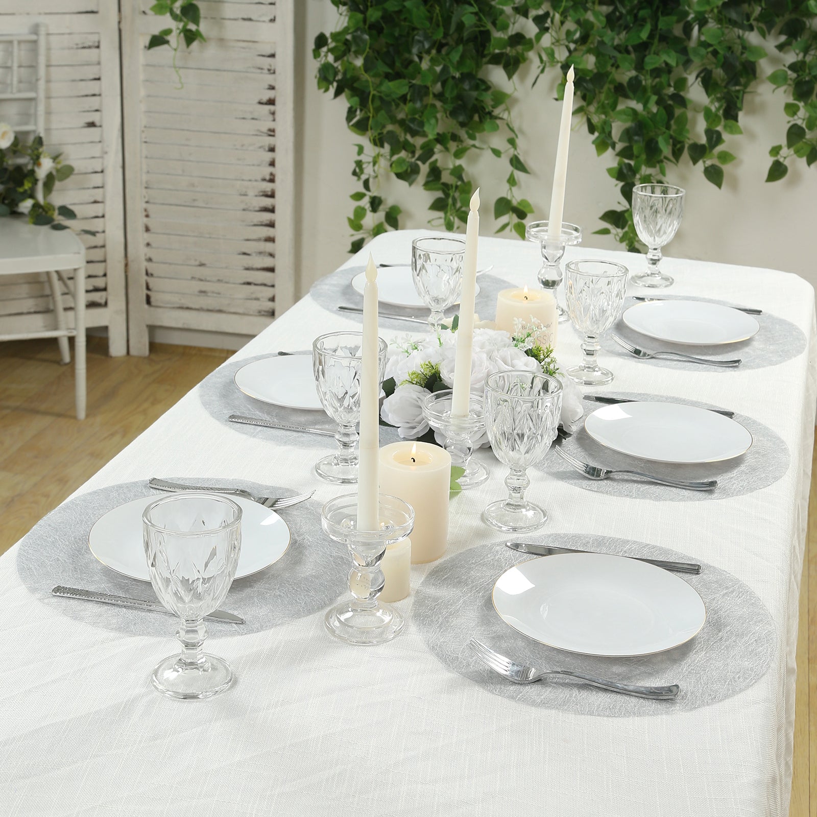 Metallic silver round placemats on a dining table setting.