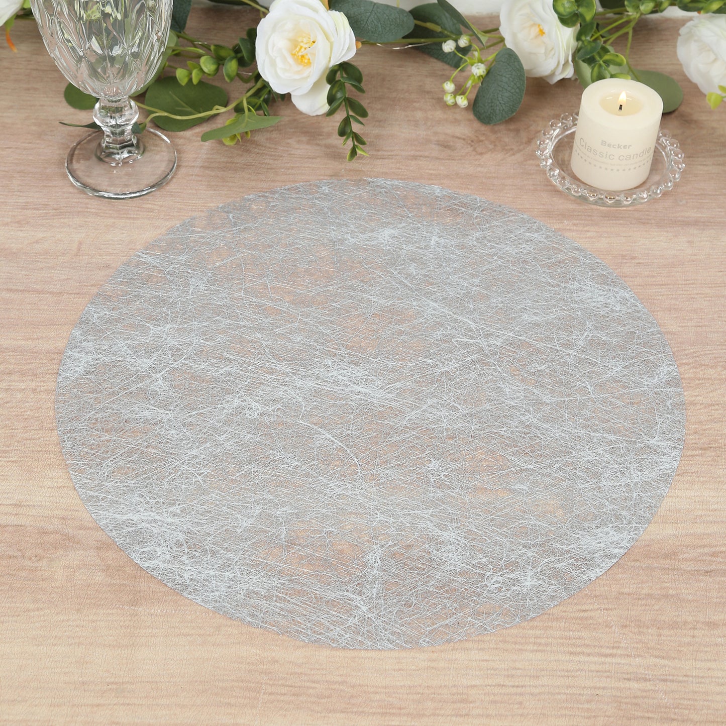 Metallic silver round placemat on a wooden table.