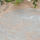 Metallic silver disposable round placemat on a wooden table.