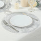 Metallic silver disposable placemat on a dining table setting.