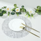 Metallic silver glitter round table mat with white plate and gold utensils.