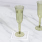 Dusty sage green plastic champagne flute on a marble surface.