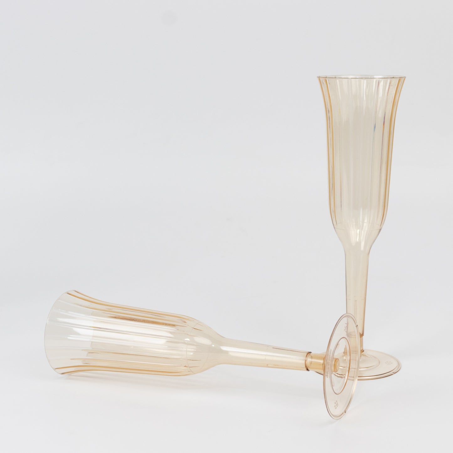 Transparent amber gold plastic champagne flutes, lightweight disposable toasting glasses.