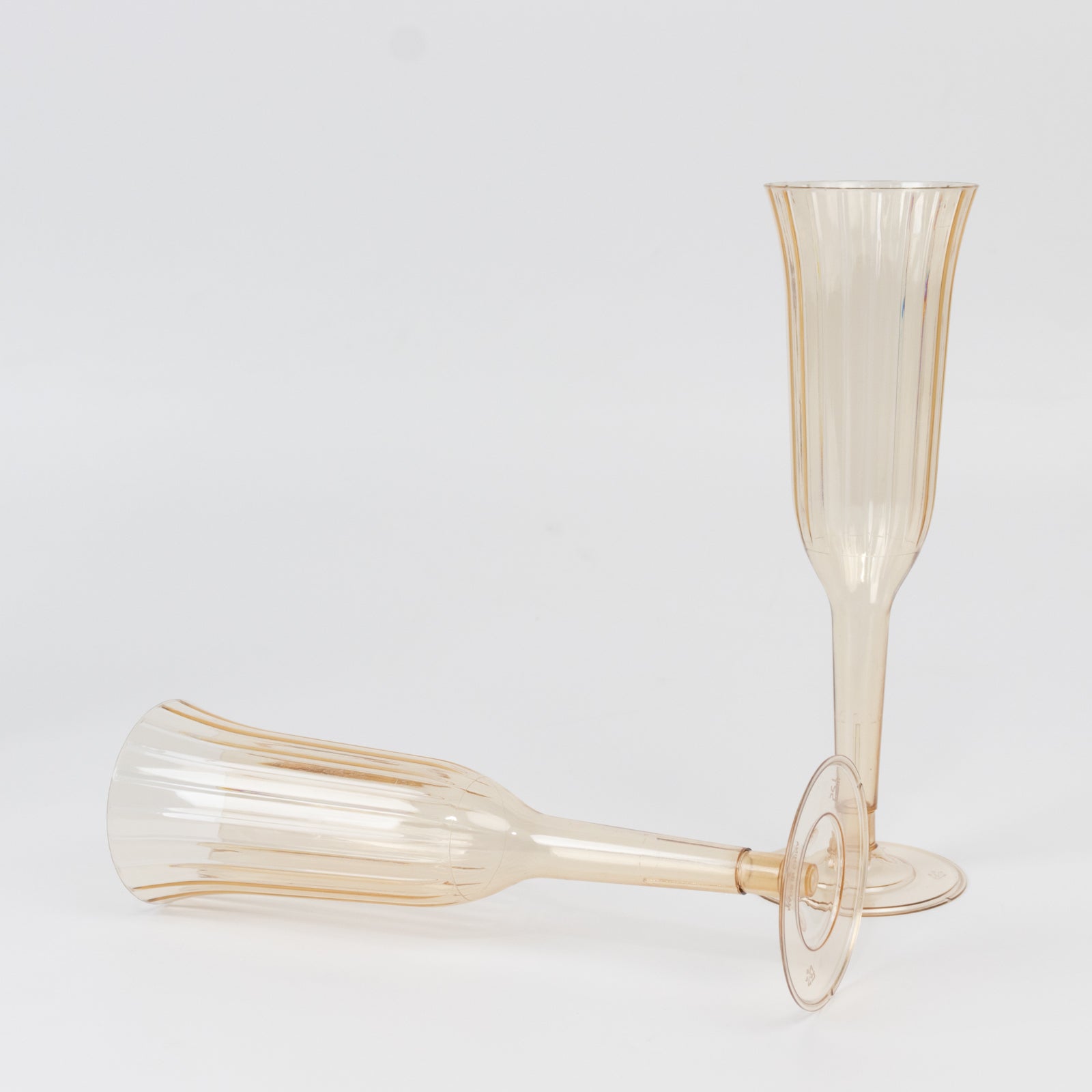 Transparent amber gold plastic champagne flutes, lightweight disposable toasting glasses.
