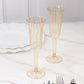 Transparent amber gold flared design plastic champagne flutes on a marble surface.