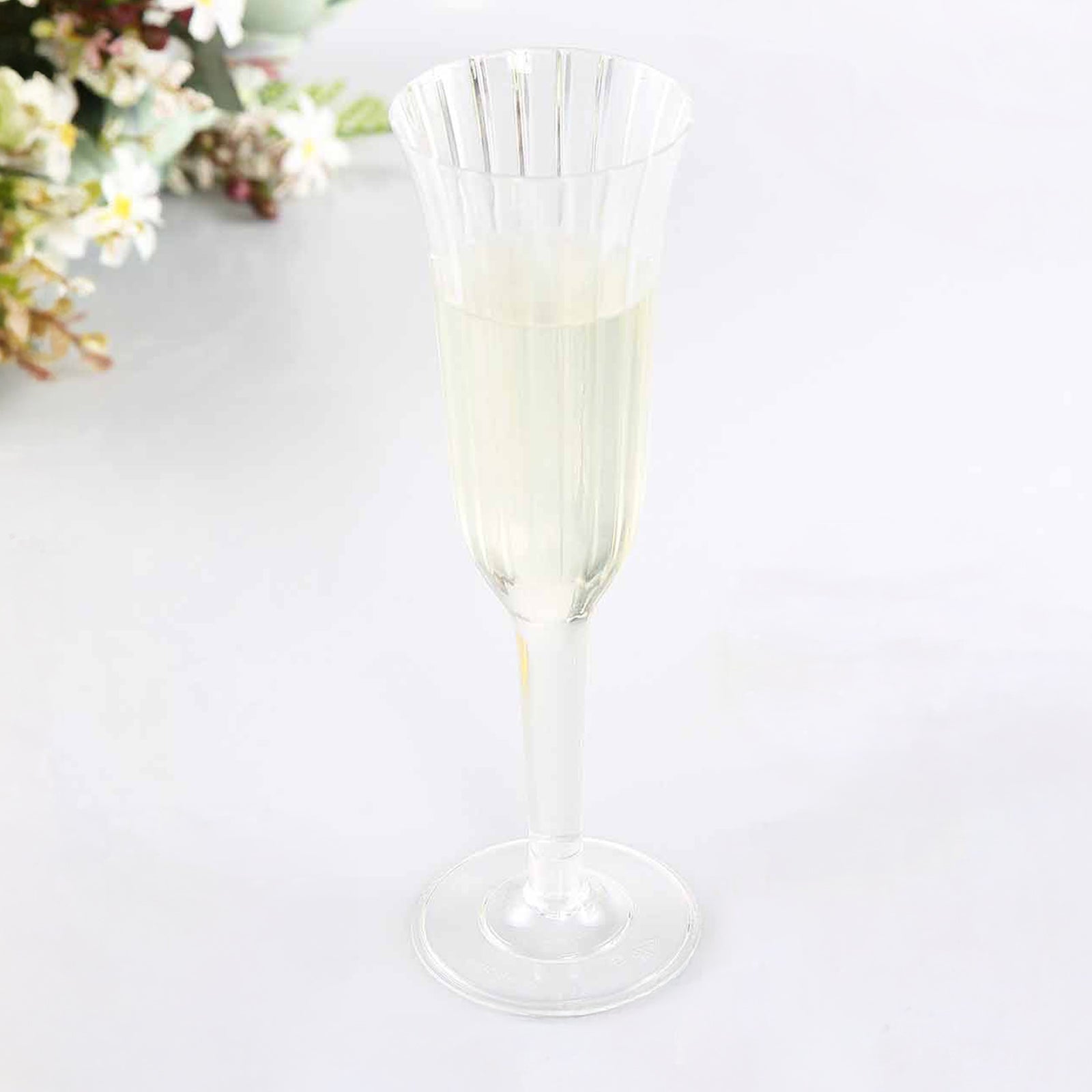 Clear plastic champagne flute with flared design, perfect for toasting.