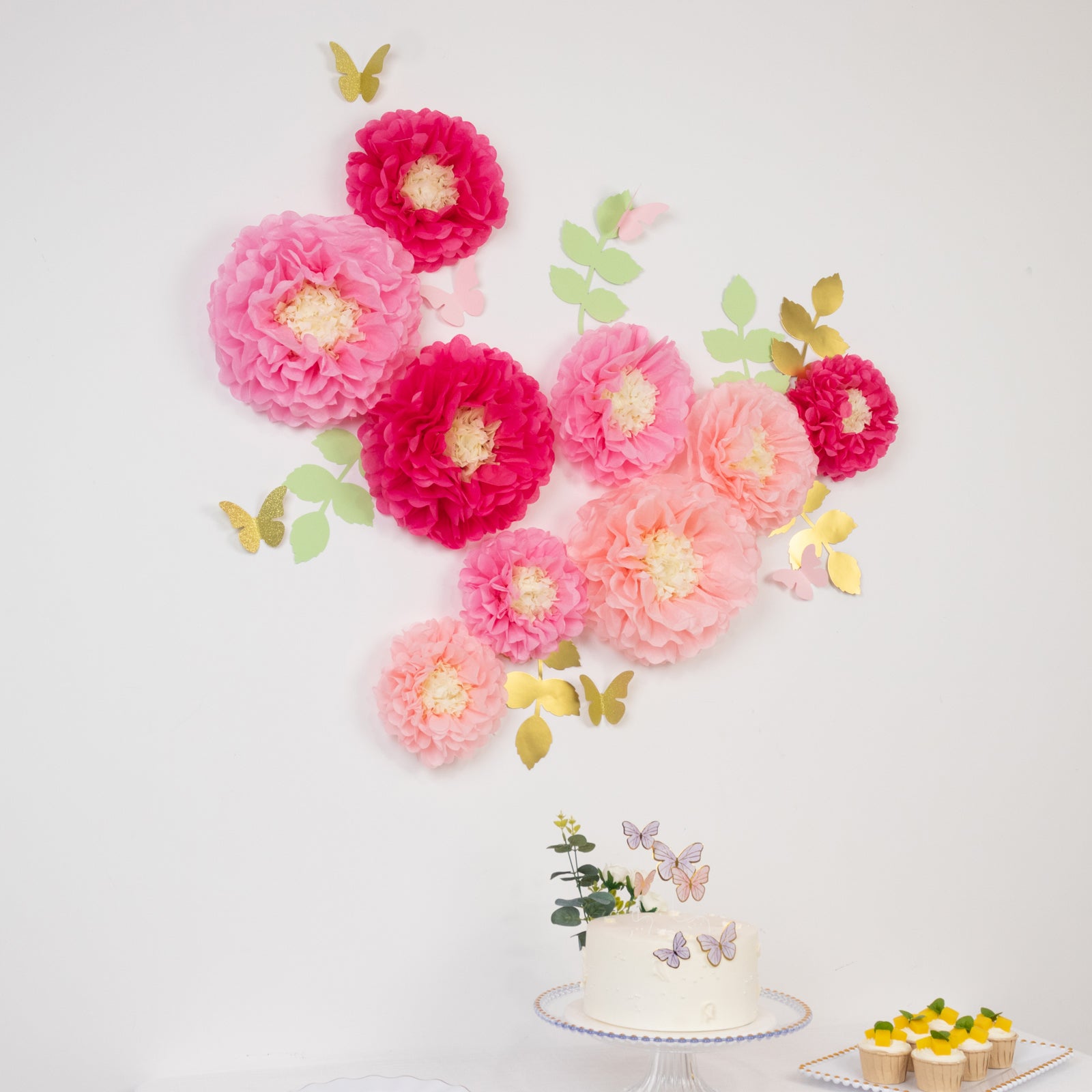 Blush pink tissue paper flowers with butterflies and olive leaves decor.