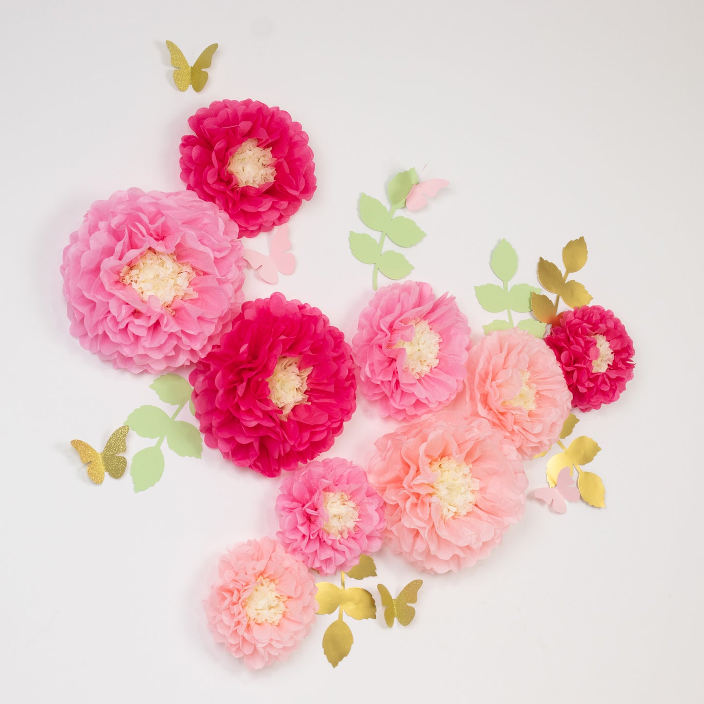 Blush pink tissue paper flowers pom poms with butterflies and olive leaves.