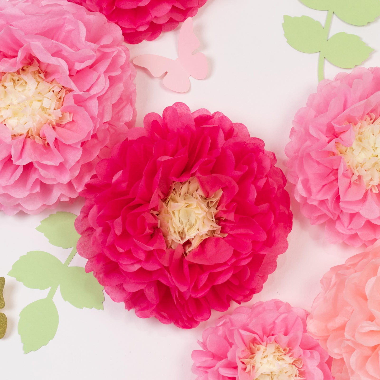 Blush pink tissue paper flowers pom poms with butterflies and olive leaves.