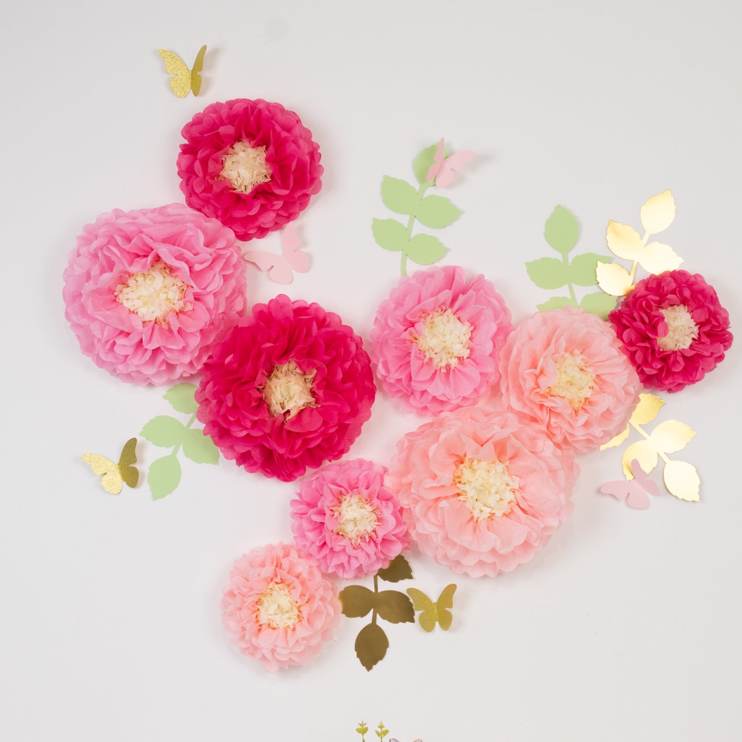 Blush pink tissue paper flowers with butterflies and olive leaves decor.