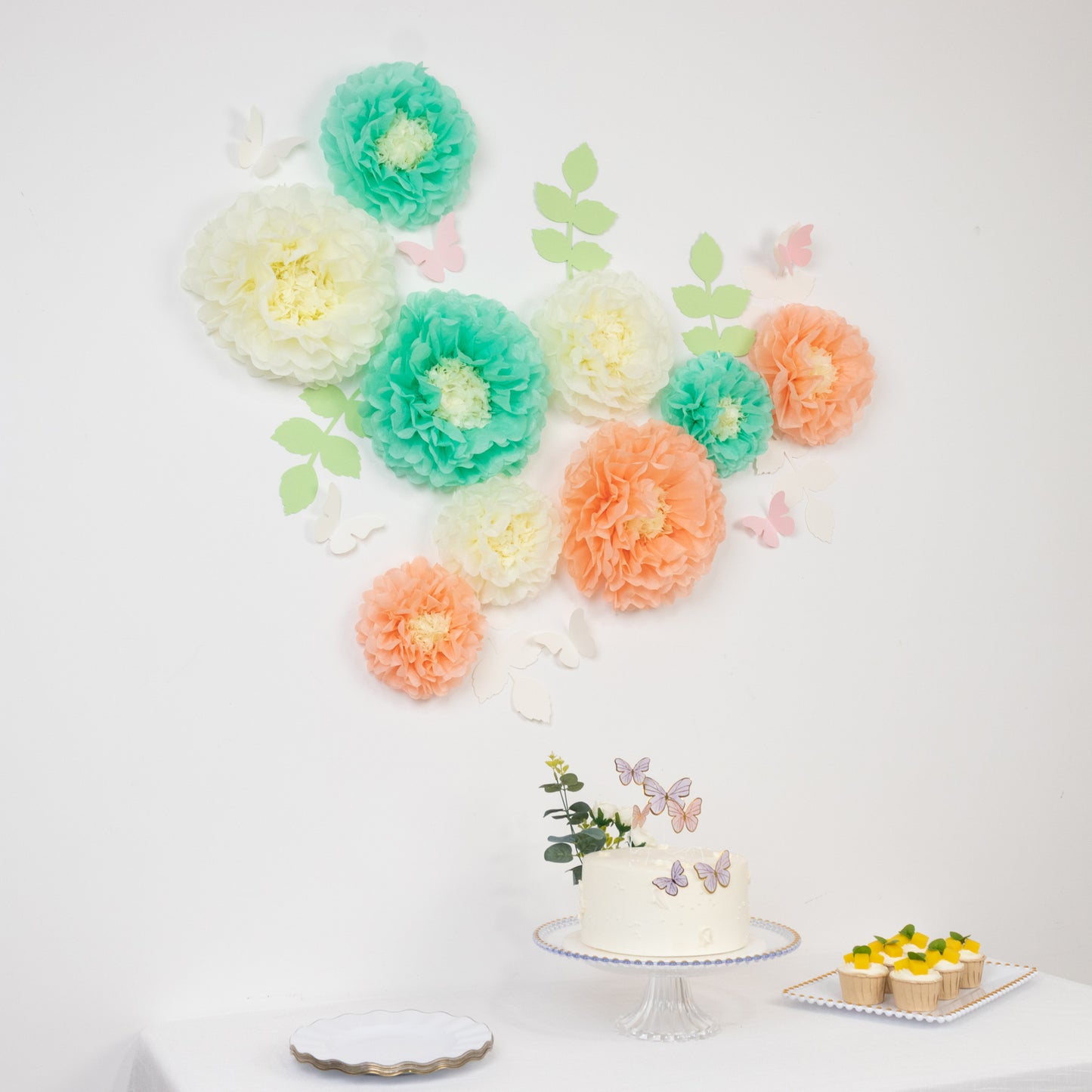 Cream and peach tissue paper flowers wall decor with butterflies and leaves.