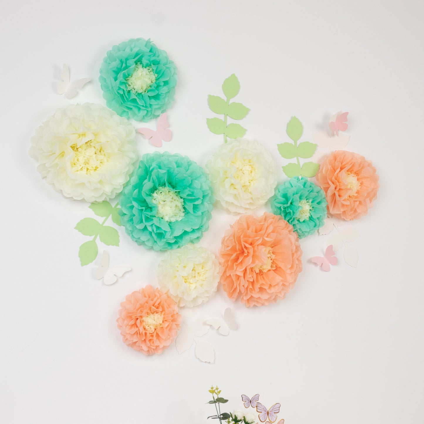 Cream and peach tissue paper flowers with butterflies and leaves wall decor.