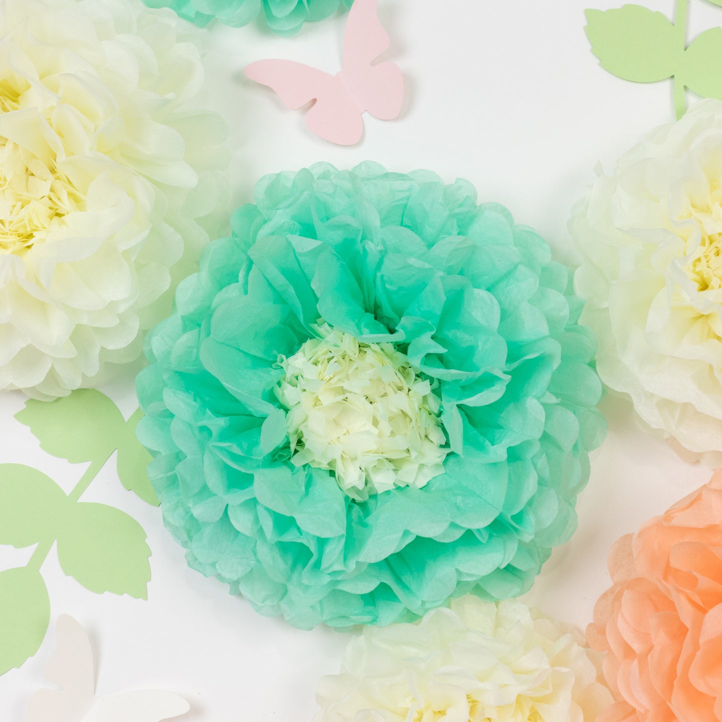 Set of 21 tissue paper flowers in cream and peach with butterflies and leaves.