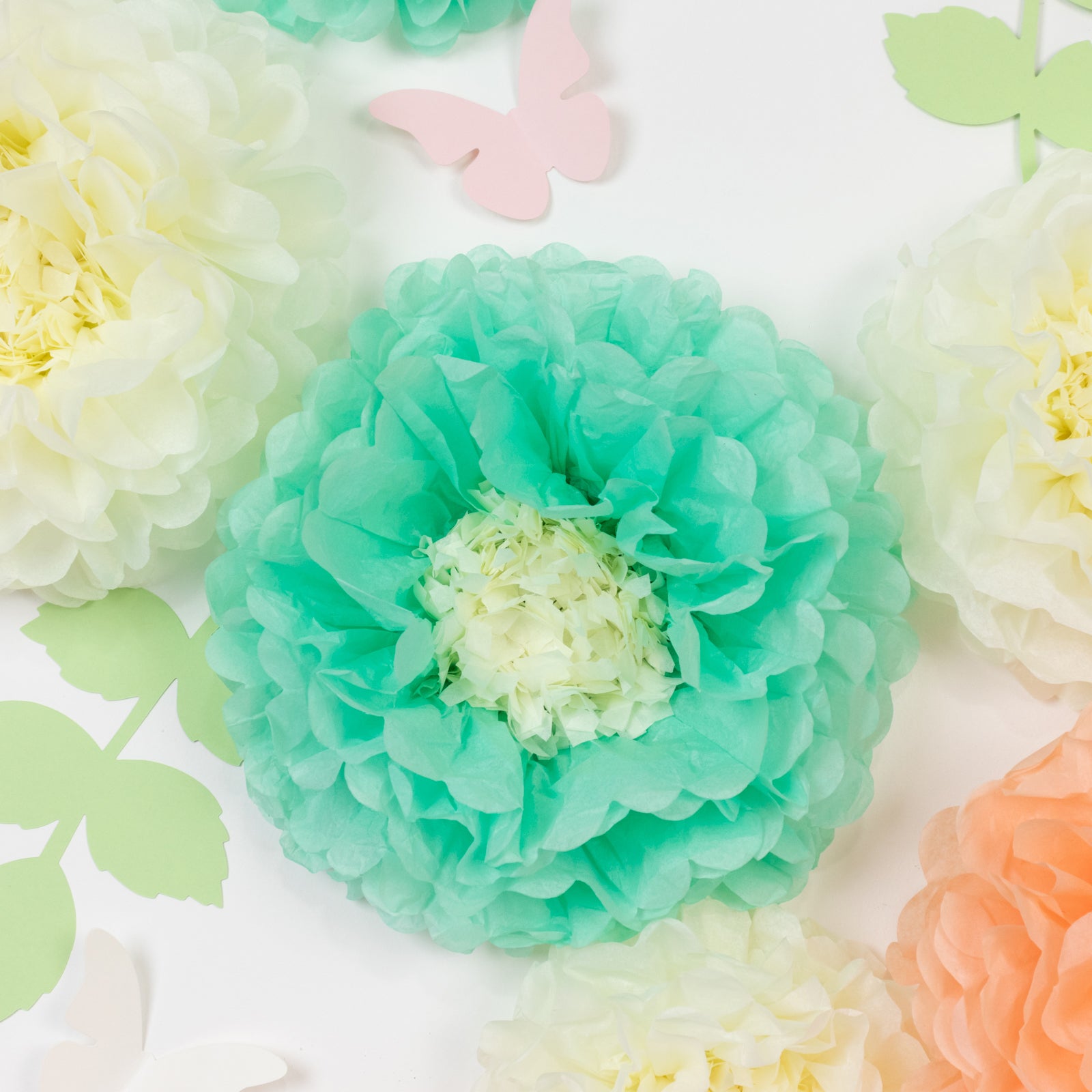 Set of 21 tissue paper flowers in cream and peach with butterflies and leaves.