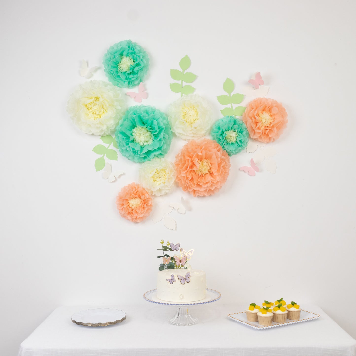 Cream and peach tissue paper pom poms with butterflies and olive leaves decor.