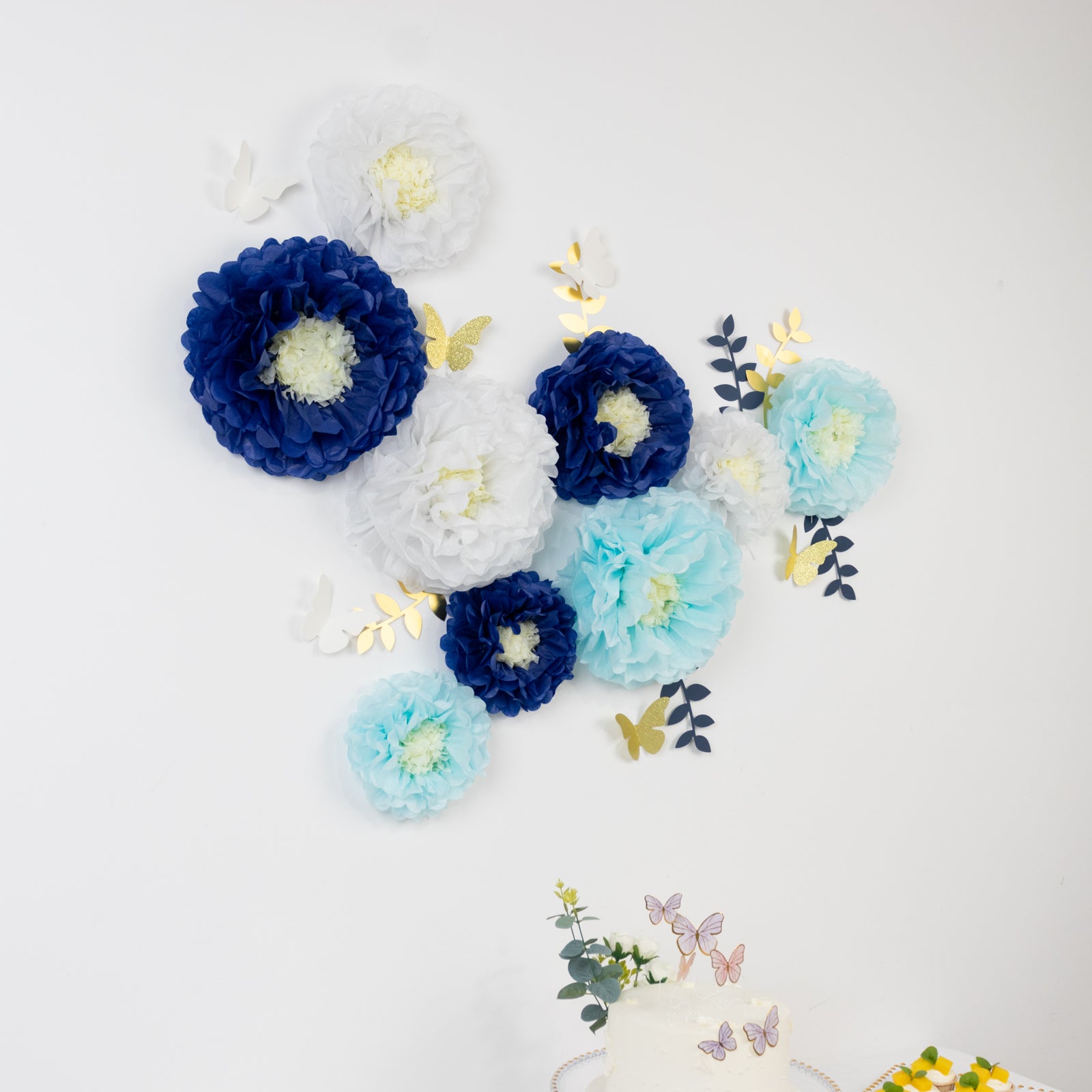 Set of blue and white tissue paper flowers with butterflies and leaves.