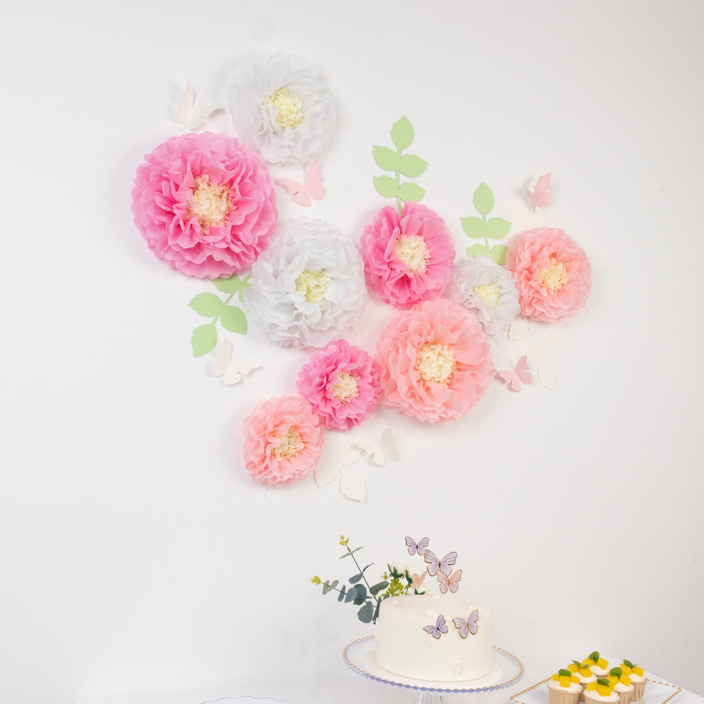 White and pink tissue paper pom poms with butterflies and olive leaves decor.
