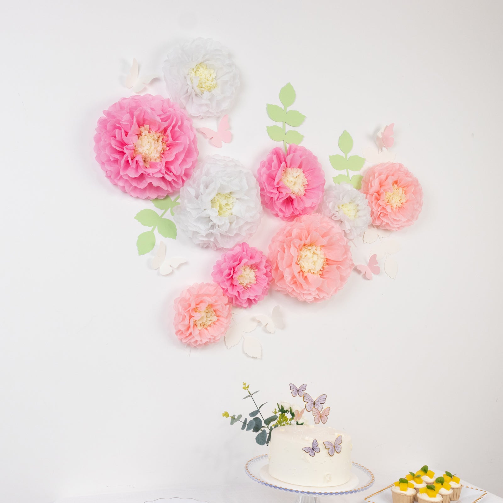 White and pink tissue paper pom poms with butterflies and olive leaves decor.