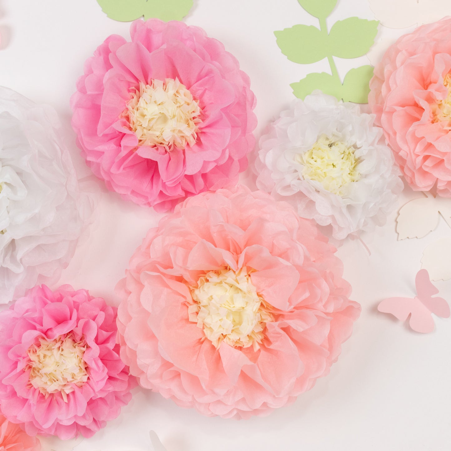 Set of pink and white tissue paper flowers with butterflies and leaves.