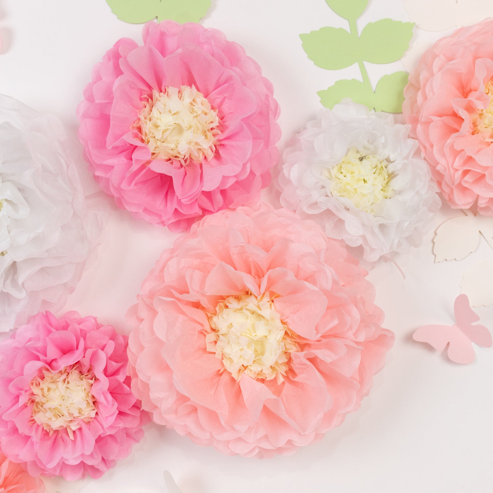 Set of pink and white tissue paper flowers with butterflies and leaves.