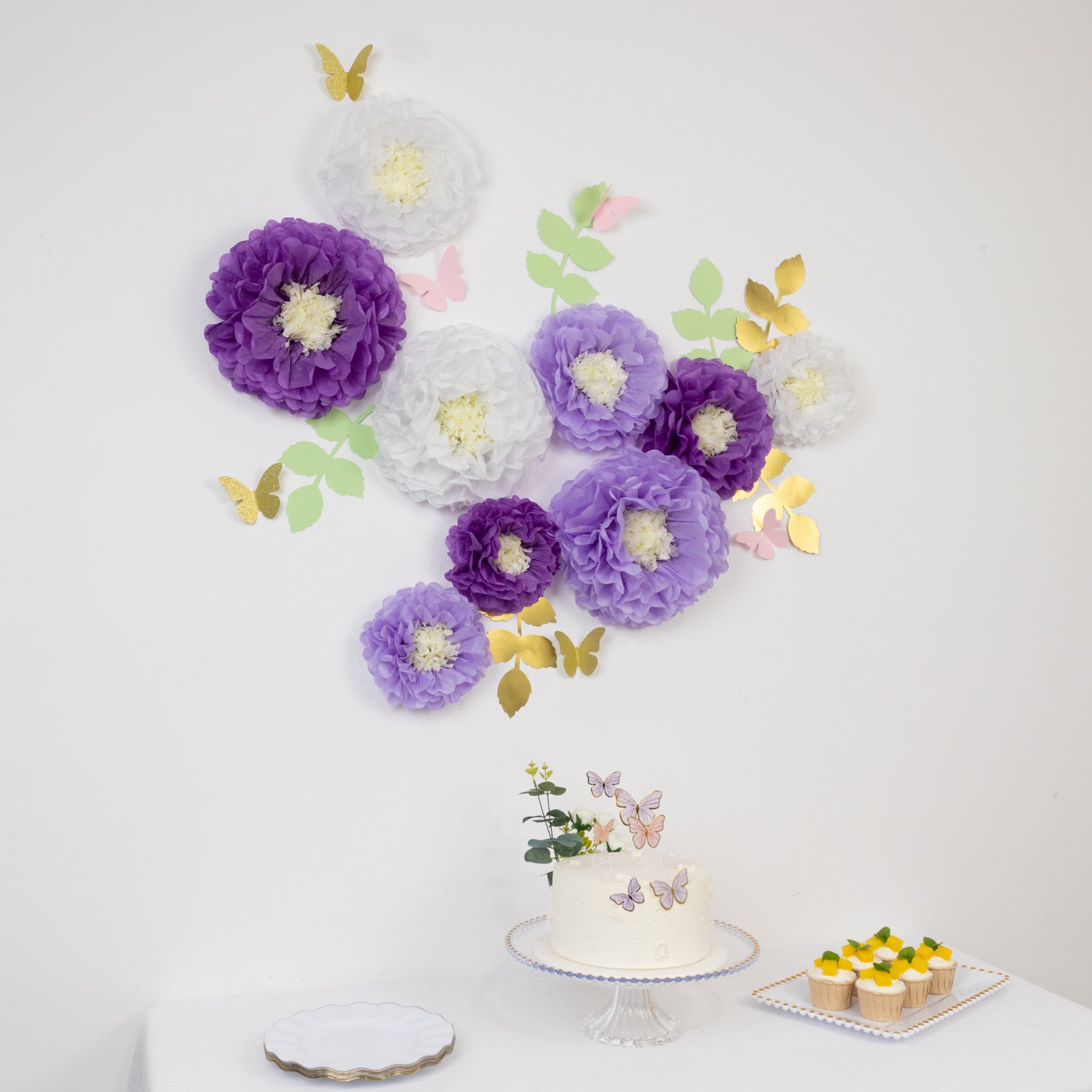 White and purple tissue paper flower pom poms with butterflies and leaves decor.