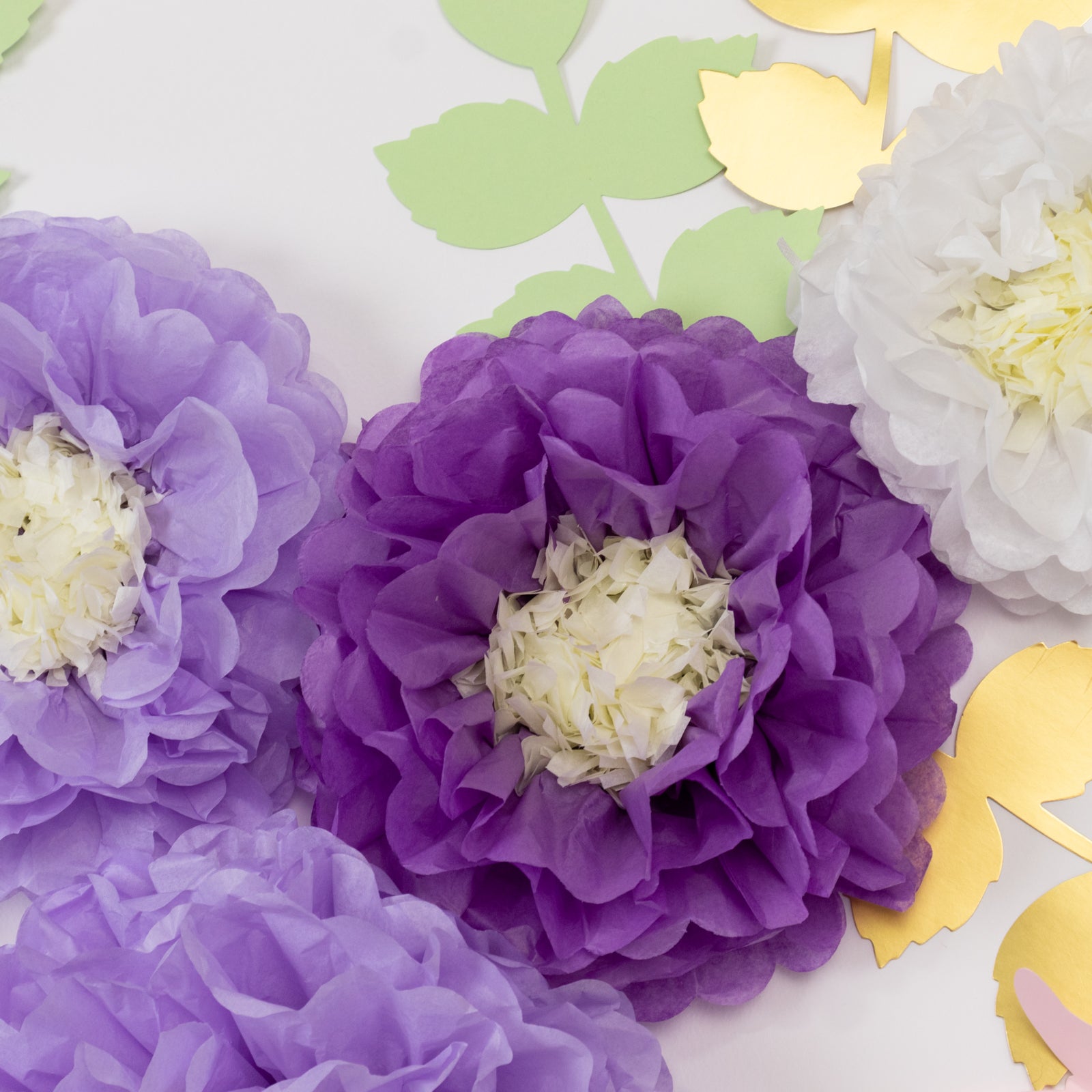 White and purple tissue paper flowers with green leaves and butterflies.