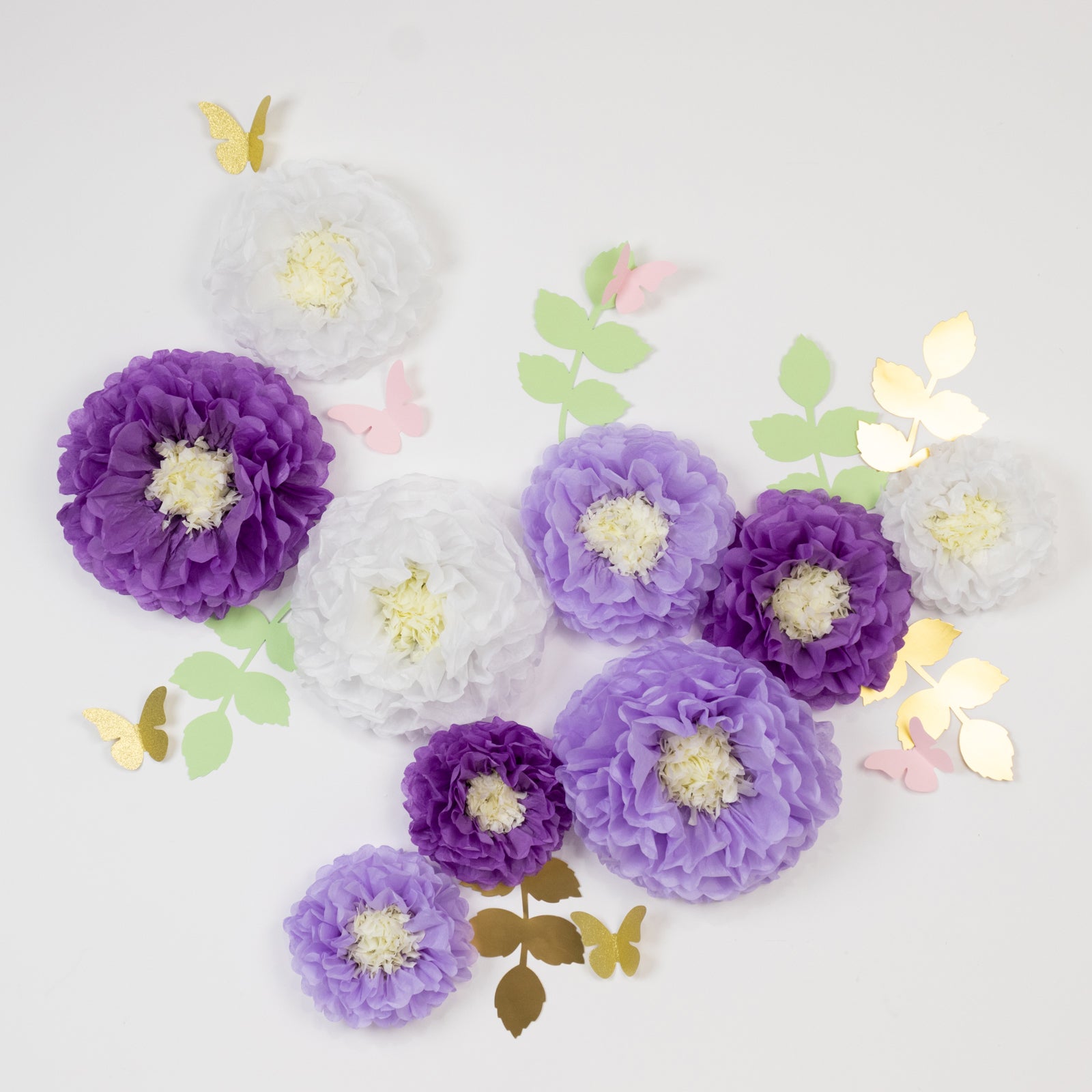 White and purple tissue paper flower pom poms with butterflies and leaves.