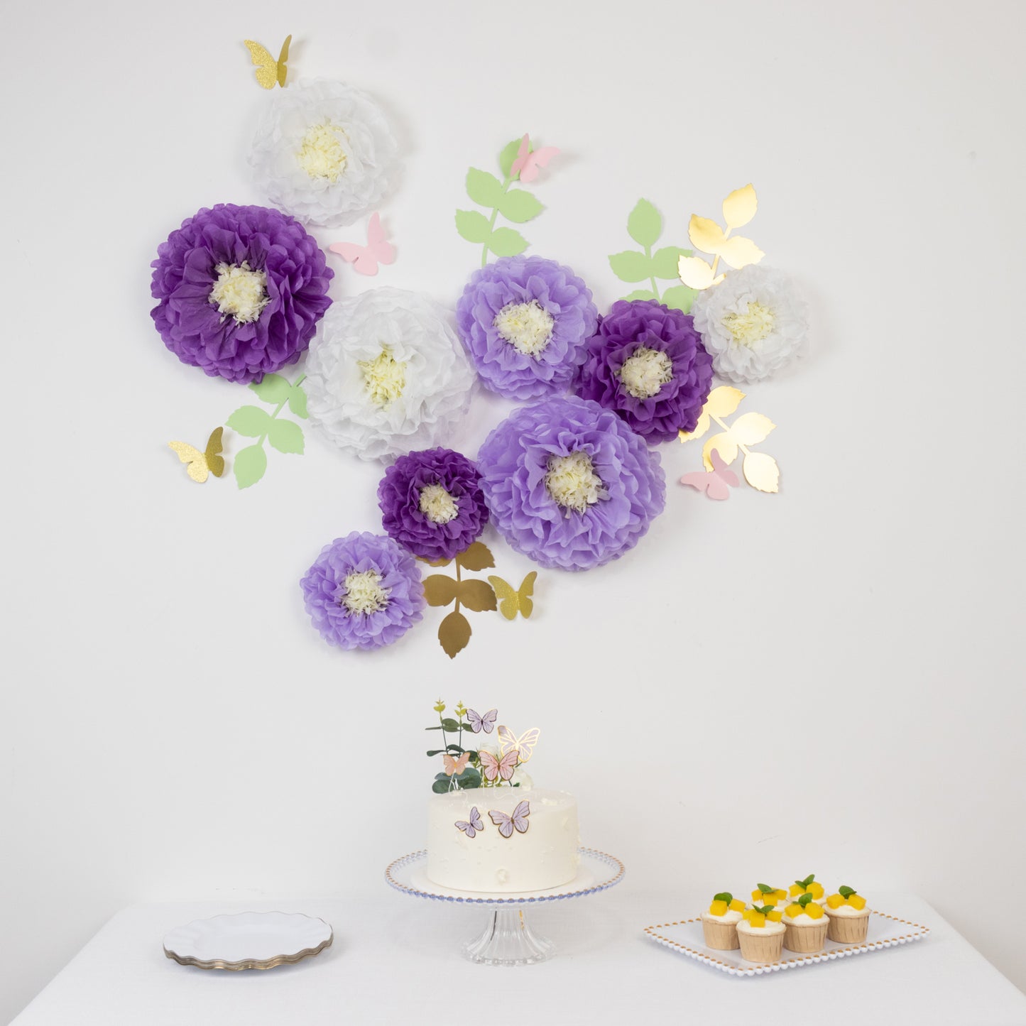 White and purple tissue paper flowers with butterflies and olive leaves wall decor.
