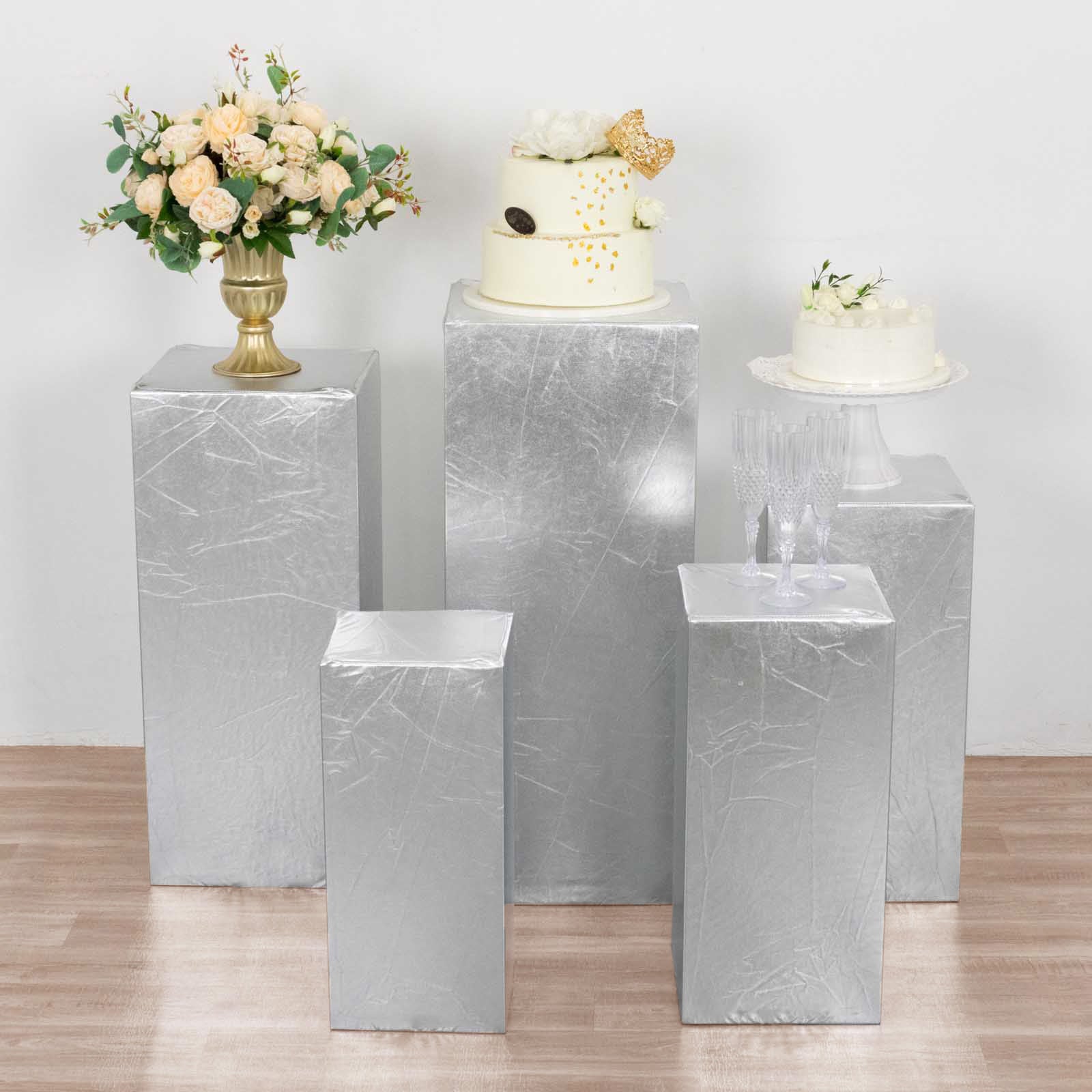 Metallic silver spandex pedestal stand covers for events and displays.