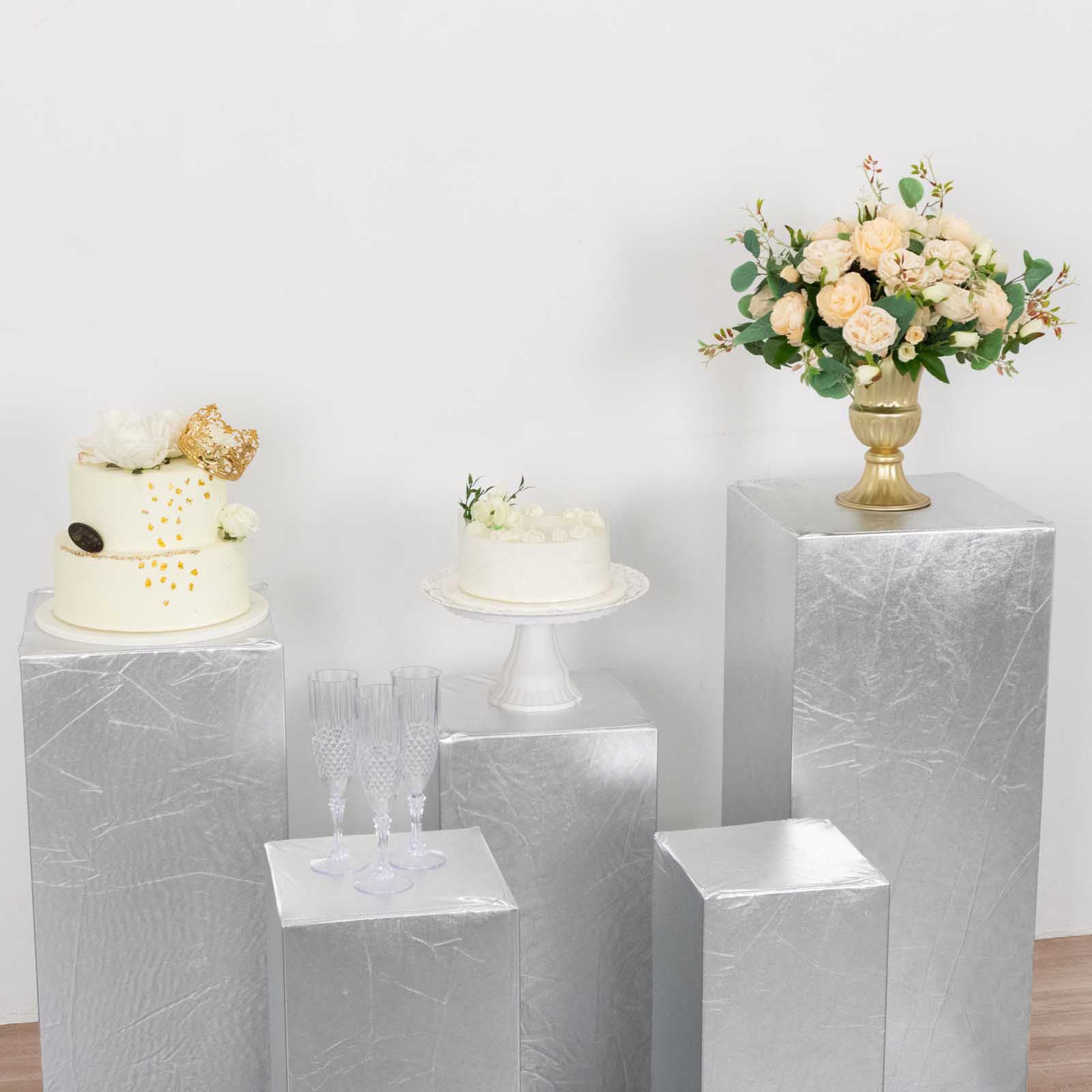 Metallic silver spandex pedestal stand covers on display with decorative items.