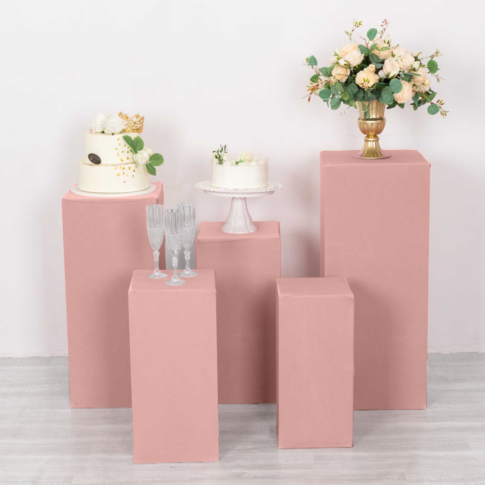 Dusty rose spandex pedestal stand covers in a stylish arrangement with floral decor.