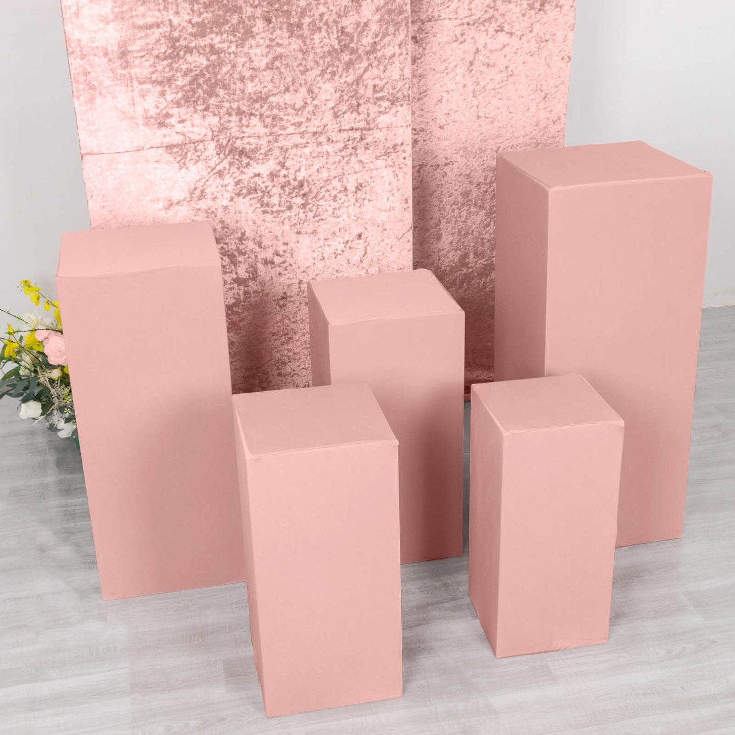 Set of 5 dusty rose spandex pedestal stand covers on display.